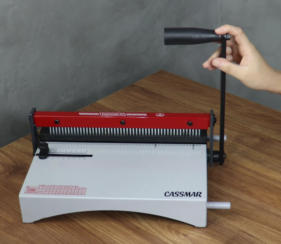 Encadernadora espiral manual Cassmar sendo utilizada para perfuração